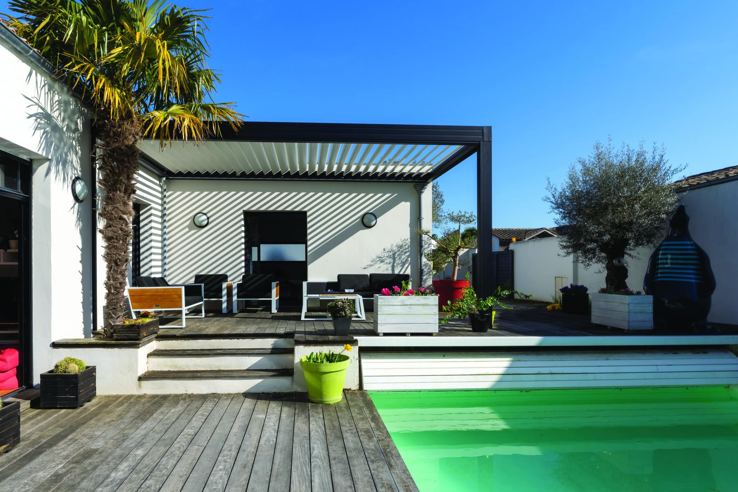 Trendy outdoor patio pergola. garden lounge, chairs, metal grill surrounded by landscaping